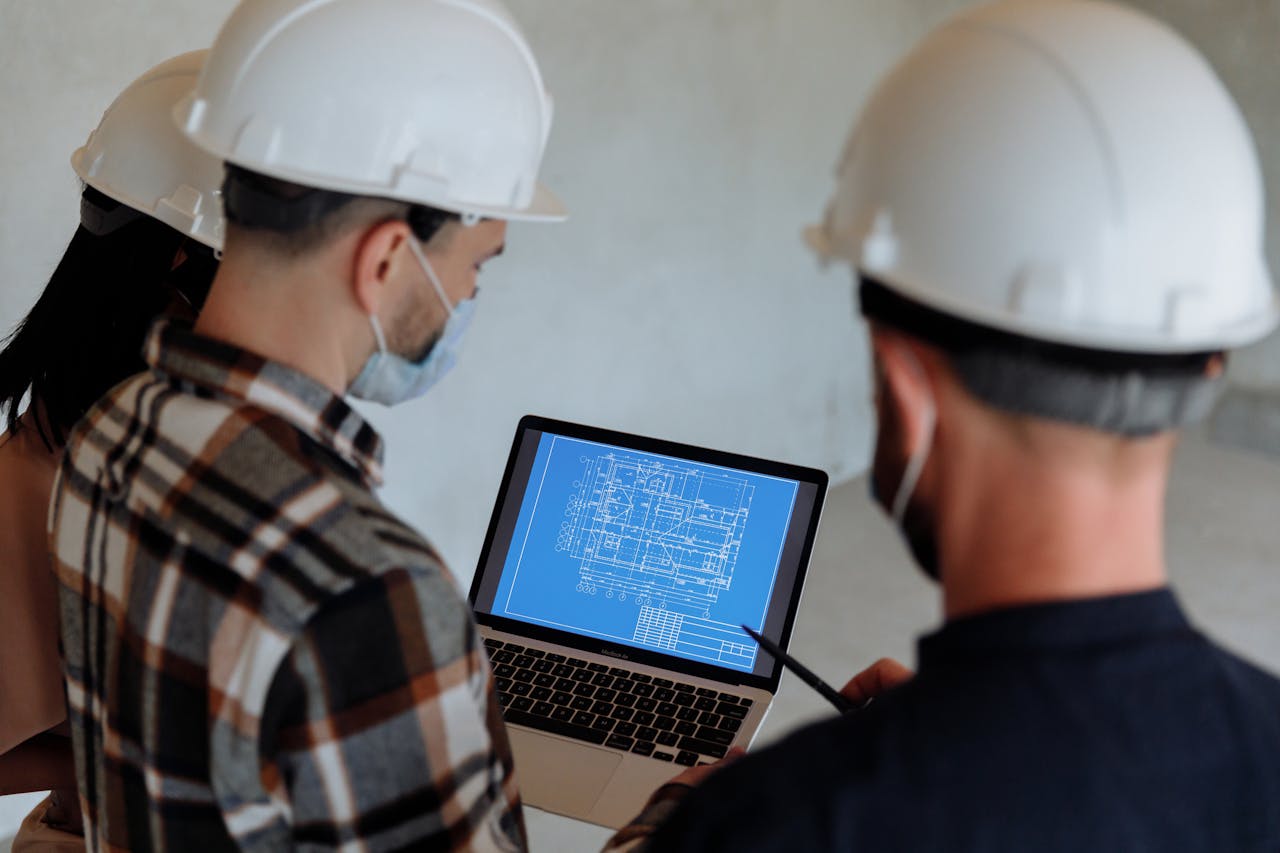 People in hard hats looking at a blueprint on a laptop